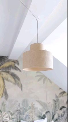 a lamp hanging from the ceiling above a bed in a room with tropical wallpaper