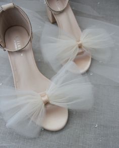 a pair of white shoes with bows on the toes and heels are sitting on a gray cloth