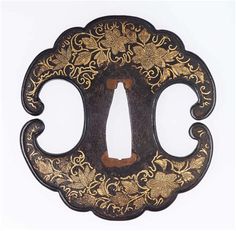 an ornately decorated black and gold metal object on a white background with clippings