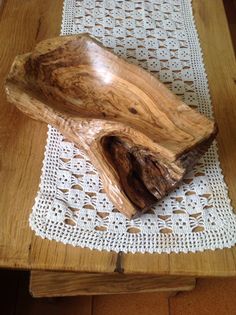 a piece of wood sitting on top of a table next to a white doily