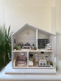 a doll house with furniture and plants in the corner next to a potted plant