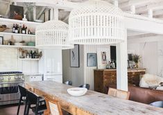 an open kitchen and dining room with white walls, wood flooring and exposed ceilings