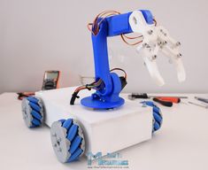 a robot that is sitting on top of a white box with wires attached to it