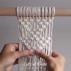 two hands are holding up a piece of white yarn