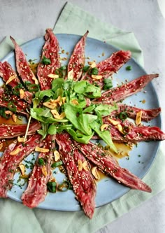 a blue plate topped with meat and veggies on top of a green cloth