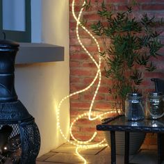 an outdoor area with a table, potted plant and light decoration on the wall