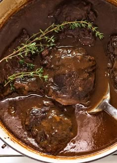 a pot filled with beef and gravy on top of a white stovetop