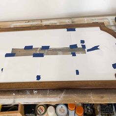 an unfinished piece of wood sitting on top of a wooden table covered in blue tape