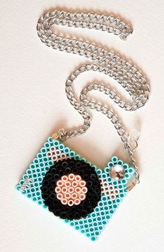 a beaded purse is hanging from a chain on a white surface with an orange and black heart in the center