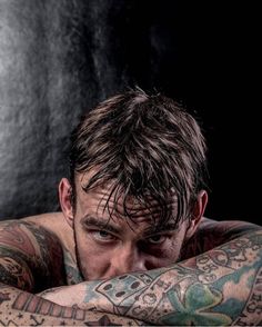 a man with lots of tattoos on his arms and chest is looking at the camera