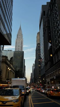 a city street filled with lots of traffic next to tall buildings in the evening time