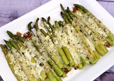 asparagus covered in cheese on a white plate