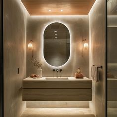 a bathroom with an oval mirror above the sink and lights on the wall behind it