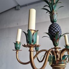 a chandelier with pineapples on it and candles hanging from the bottom