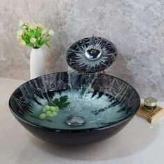 a bowl shaped sink with water running down it's side and flowers in the background