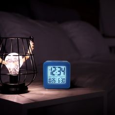 an alarm clock sitting on top of a table next to a night stand with a light bulb