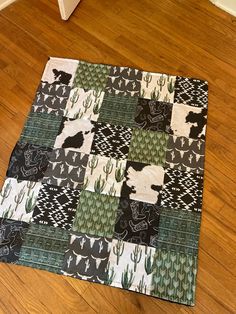 a black and white cat sitting on top of a wooden floor next to a rug