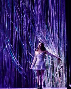 a woman standing in front of a purple curtain with streamers on it's sides