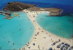 an aerial view of a beach with many people and boats in the water, surrounded by blue waters