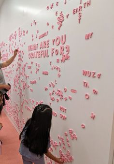 two girls are writing on the wall with pink letters