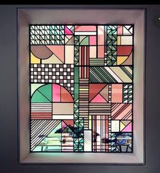 a colorful stained glass window in a white frame with an abstract geometric design on it