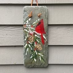 a stone sign with a cardinal and pine cones on it hanging from the side of a house