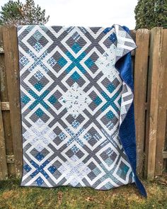 a blue and grey quilt on a wooden fence