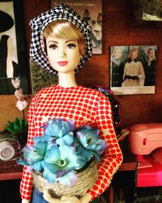 a barbie doll holding a basket with flowers in it's hands and wearing a hat