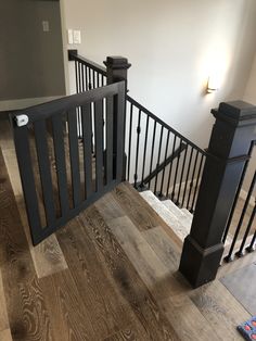 an open staircase with black railings and wood flooring in a new construction home