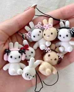 a person is holding several small key chains in their hand, some are wearing bunny ears and bow ties