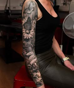 a woman sitting on top of a red chair with a butterfly tattoo on her arm