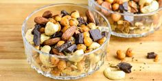 two clear bowls filled with nuts on top of a wooden table next to each other