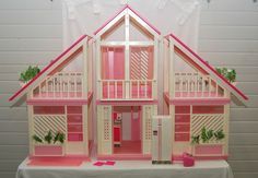 a doll house with pink and white trim on the roof, windows, and balconies