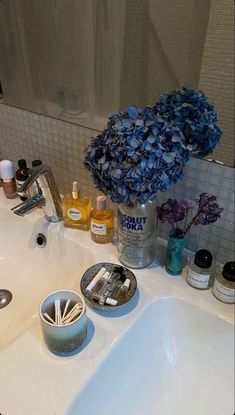 a bathroom sink with soap, toothbrushes and flowers on it