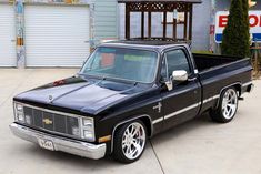 a black pickup truck parked in front of a garage