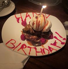 a birthday cake with ice cream, raspberries and chocolate sauce on a white plate