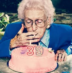 an old woman blowing out the candles on her birthday cake