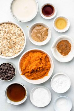 bowls filled with different types of food on top of a white countertop next to spoons