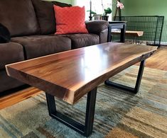 a wooden table sitting on top of a carpeted floor next to a brown couch