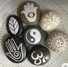 five rocks with symbols painted on them in a bowl