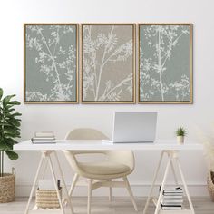 a white desk with a laptop computer on top of it next to two framed pictures