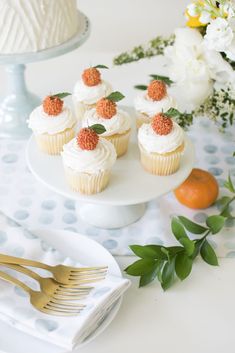 cupcakes with white frosting and strawberries on top sitting on a plate