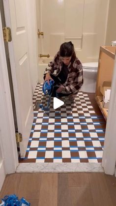 a woman kneeling on the floor in front of a bathroom