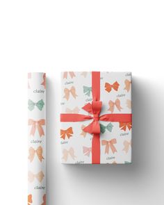 a present wrapped in paper and tied with a red ribbon on top of a white surface