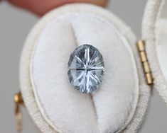 a blue diamond sitting on top of a white cushion in a case with gold trimmings