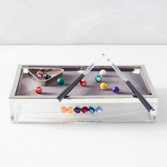 a pool table with marbles, cues and balls in it on a white surface