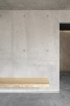 an empty concrete room with a wooden bench