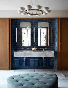 a modern bathroom with blue tile walls and flooring, including a round foot stool