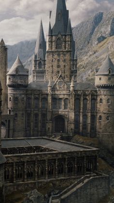 an old castle with towers and spires in the middle of a mountain range, surrounded by mountains