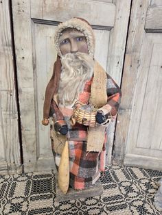 a statue of an old man with a long beard and wearing a plaid coat is standing in front of a wooden door